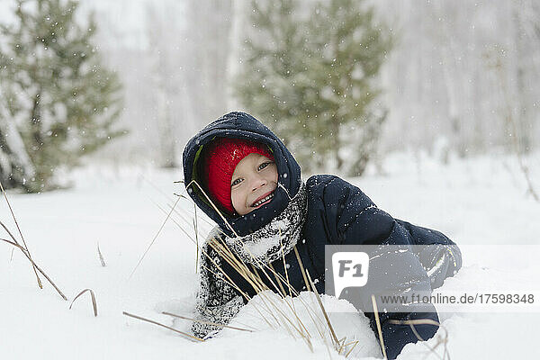 Happy boy playing in snowy forest