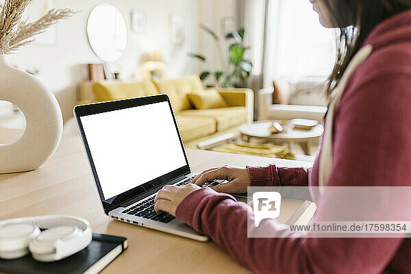 Woman typing on laptop in living room at home