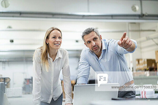 Businessman pointing away by blond businesswoman in industry