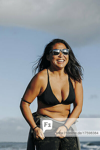 Happy woman wearing wetsuit and bikini at beach
