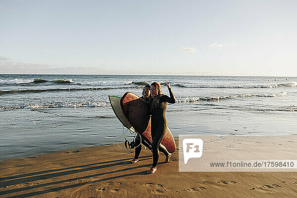 Fröhliche Surferinnen mit Surfbrettern  die am Strand von Gran Canaria  Kanarische Inseln  auf dem Sand spazieren