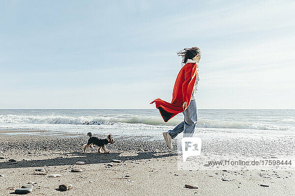 Young woman with dog looking at sea on sunny day