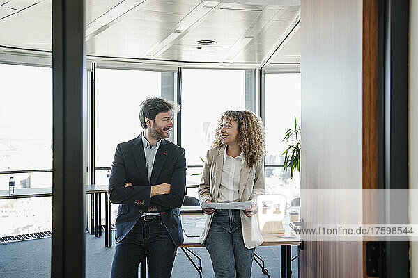 Smiling businessman and businesswoman looking at each other in office