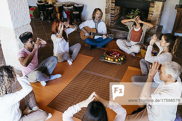 Multiracial friends meditating in music therapy at farmhouse