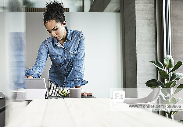 Young businesswoman working on tablet computer at desk in office