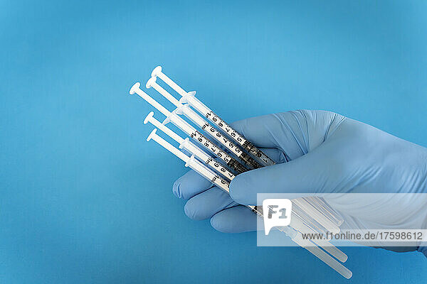 Medical expert holding syringes against blue background