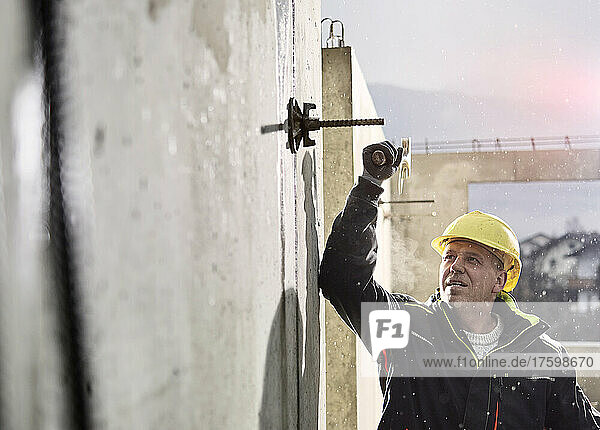 Worker with hammer loosening iron rod on concrete wall