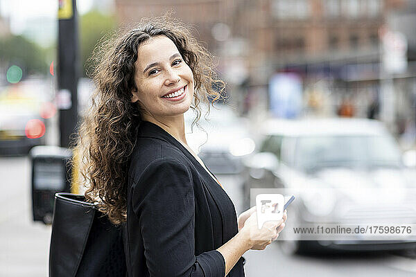 Happy businesswoman with smart phone and purse