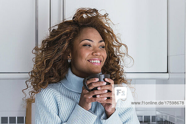 Smiling woman with coffee cup at home
