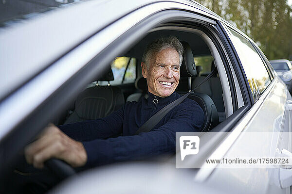 Smiling senior man driving car
