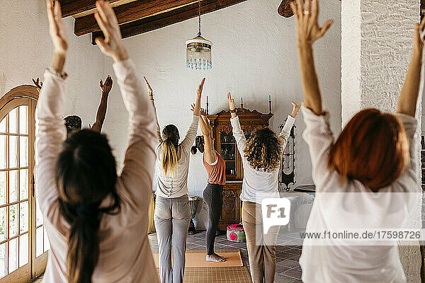 Freunde und Yogalehrer strecken im Yogastudio die Hände aus