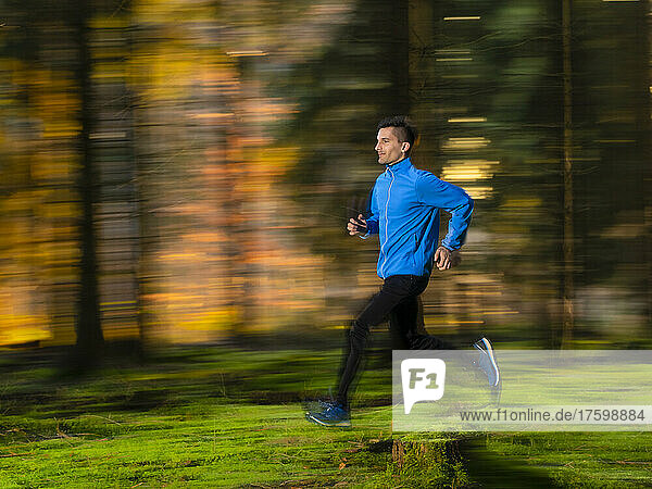 Dedicated young man jogging in forest