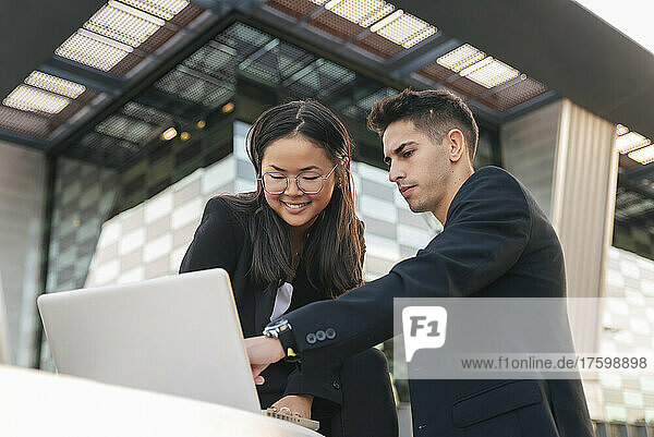 Businessman explaining colleague using laptop