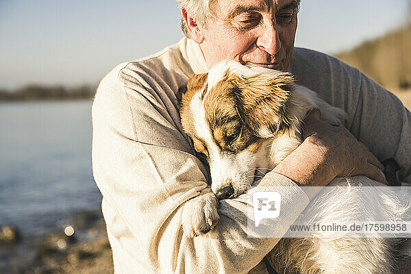 Älterer Mann umarmt Hund an sonnigem Tag