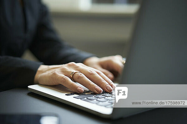 Businesswoman's hands typing on laptop in office