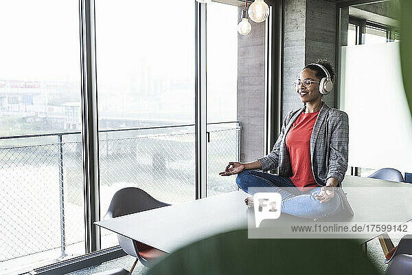 Businesswoman listening music and meditating at work place
