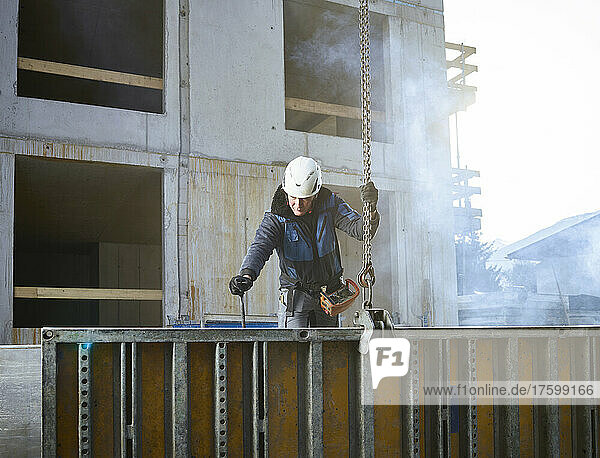 Worker holding chain attached with construction material at site