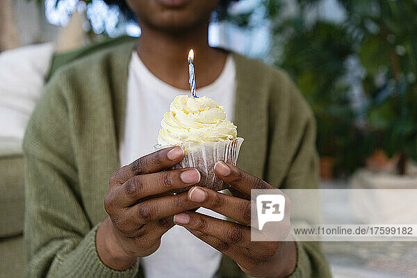 Young woman with candle on cupcake on birthday