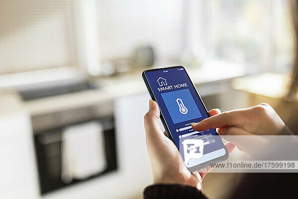 Woman using smart home application on mobile phone at home