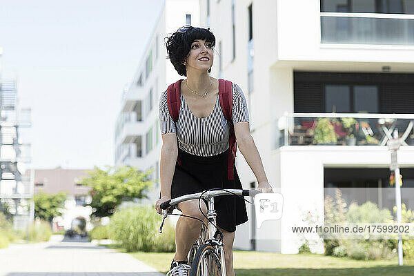 Smiling woman riding bicycle on street in city