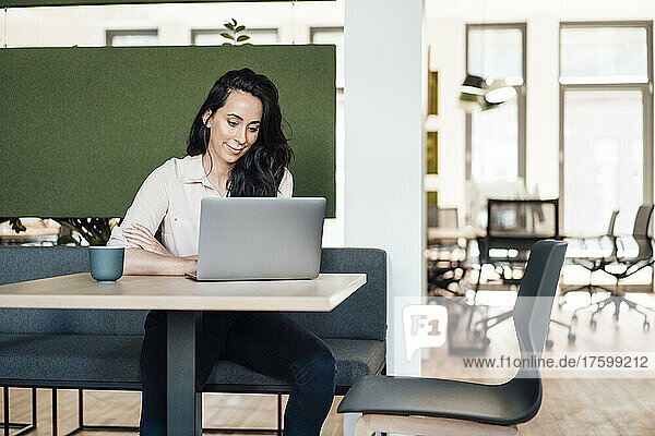 Businesswoman using laptop at desk in coworking office