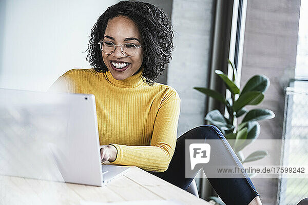 Glückliche Geschäftsfrau  die Laptop am Arbeitsplatz benutzt