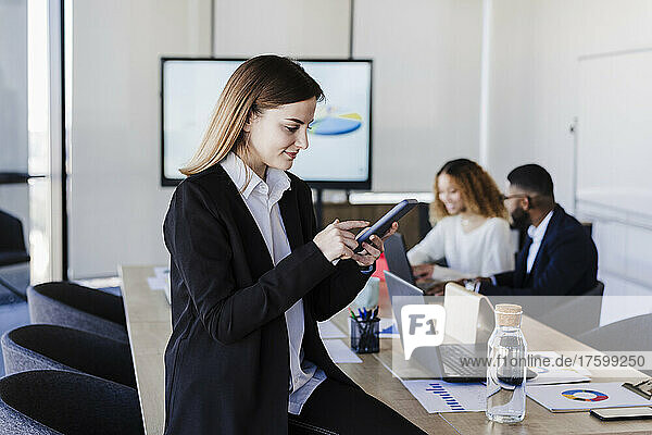 Geschäftsfrau benutzt Smartphone im Sitzungssaal eines Coworking-Büros