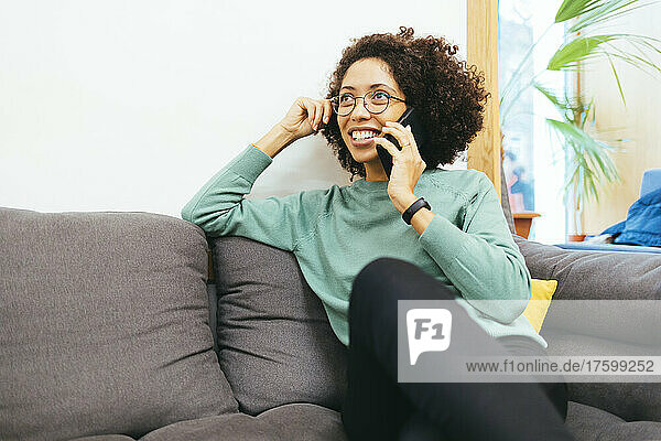 Smiling woman talking on mobile phone on sofa