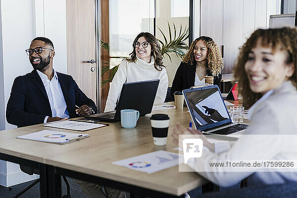 Multiethnische Geschäftskollegen nehmen an einer Besprechung teil und sitzen am Schreibtisch im Coworking-Büro