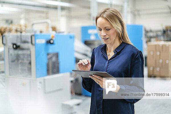 Blond businesswoman using tablet PC working in factory