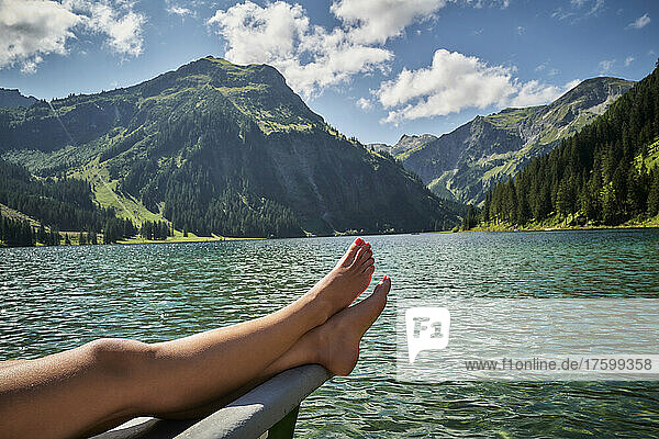 Woman's legs on prow of rowboat in lake