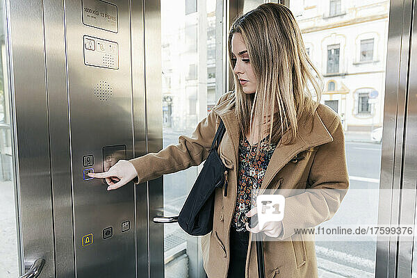 Blonde Frau drückt Knopf im Aufzug