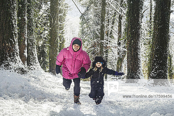 Father and daughter running on snow enjoying in forest