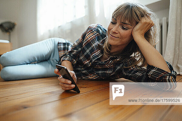 Woman with bangs using smart phone on floor at home