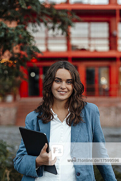 Smiling businesswoman with brown hair holding tablet PC