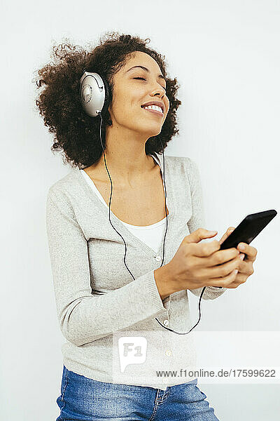 Woman listening music through headphones against white background