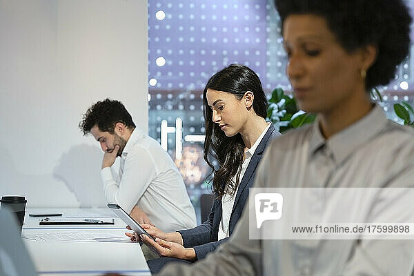 Junge Geschäftsfrau arbeitet mit Kollegen im Büro am Tablet-PC