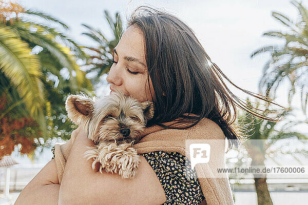 Woman hugging Yorkshire Terrier on sunny day