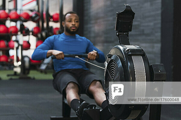 Athlete exercising on rowing machine in gym