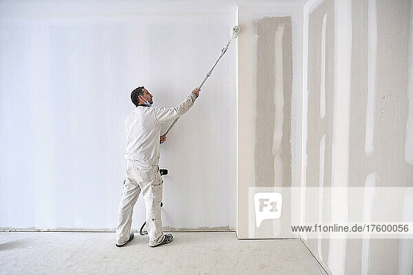 Painter painting wall with roller at construction site