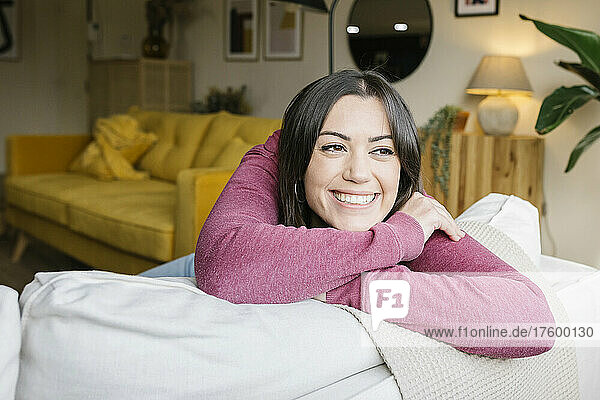 Happy beautiful woman leaning on sofa at home