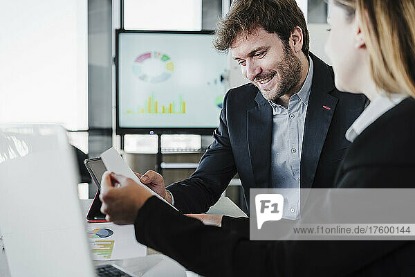 Smiling businessman discussing report with colleague in office