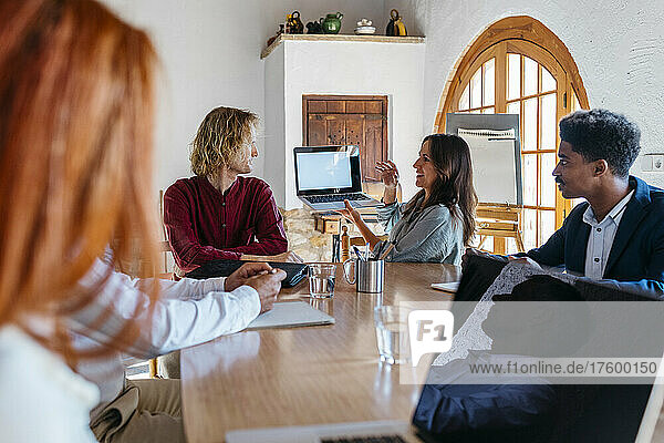 Businesswoman giving presentation on laptop to colleagues in board room