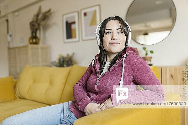 Beautiful woman listening music through wireless headphones in living room