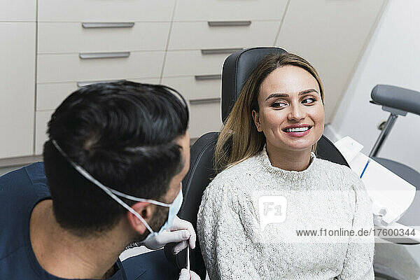 Zahnarzt diskutiert mit Patient  der auf dem Zahnarztstuhl in der Klinik sitzt