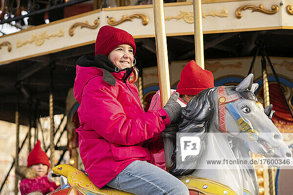 Smiling girl enjoying carousel ride at Christmas market