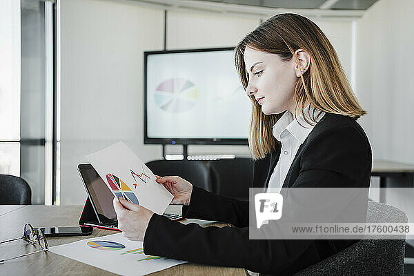 Businesswoman reading report at desk in office
