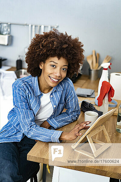 Smiling young Afro woman using tablet PC at kitchen counter