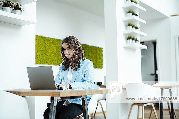 Businesswoman working on laptop sitting at desk in office