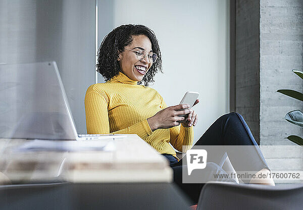 Cheerful businesswoman using smart phone in office